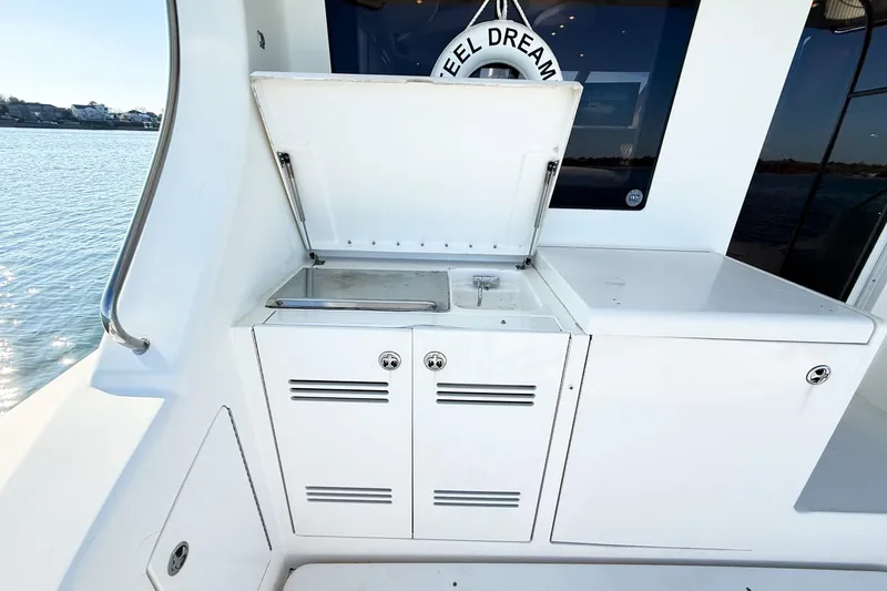 Slide: The Image of 2004 Silverton 48 Convertible yacht with outdoor sink and storage, docked by the water. - 26