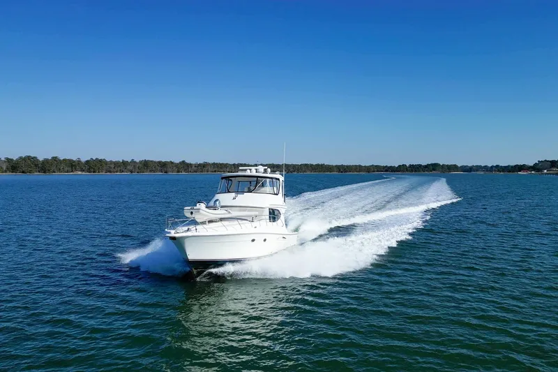 Slide: The Image of 2004 Silverton 48 Convertible yacht cruising on open water under clear blue skies. - 3