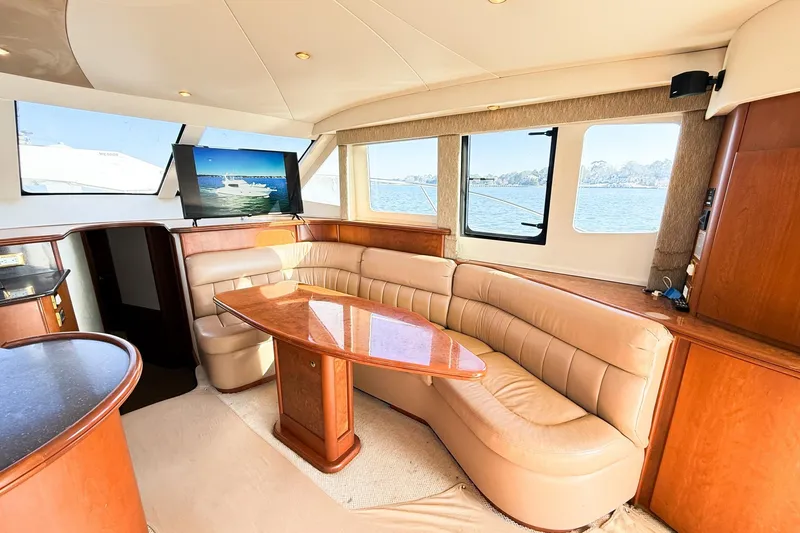 Slide: The Image of Luxurious interior of 2004 Silverton 48 Convertible yacht with leather seating and wooden table. - 34