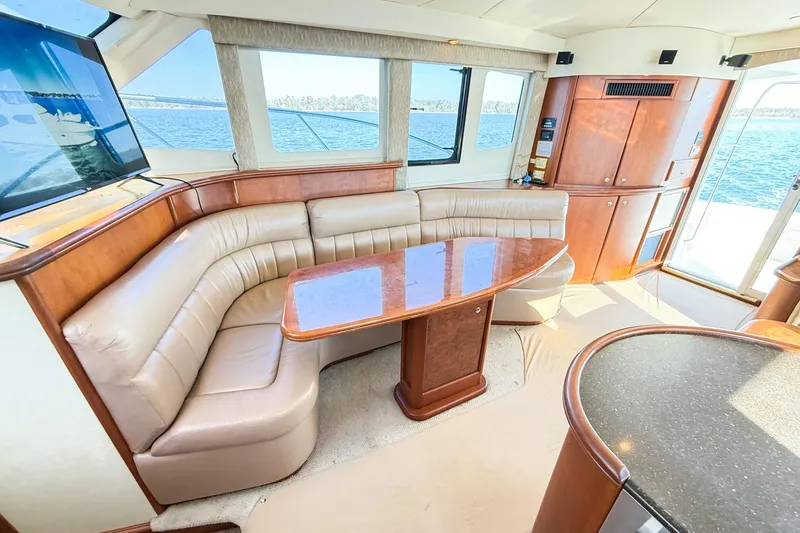 Slide: The Image of Luxurious interior of a 2004 Silverton 48 Convertible yacht with leather seating and wooden table. - 36