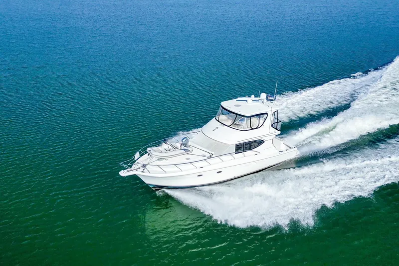 Slide: The Image of 2004 Silverton 48 Convertible yacht cruising on open water, creating a wake. - 4