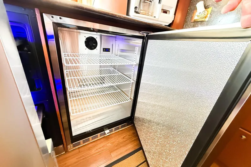 Slide: The Image of Open refrigerator inside 2004 Silverton 48 Convertible yacht, featuring wire shelves and modern design. - 48