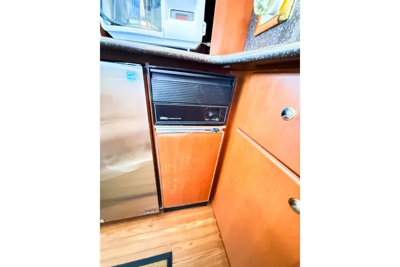 Slide: The Image of 2004 Silverton 48 Convertible yacht kitchen with wooden cabinets and compact appliances. - 49