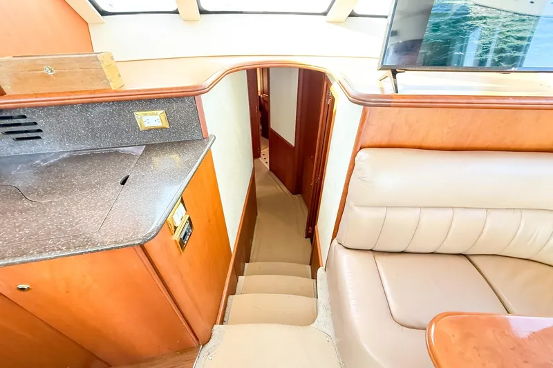 Slide: The Image of Interior of 2004 Silverton 48 Convertible yacht with stairs, leather seating, and countertop. - 52