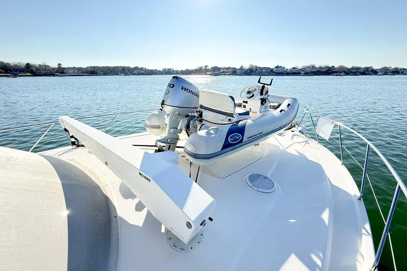 Slide: The Image of 2004 Silverton 48 Convertible yacht with dinghy on deck, cruising on calm waters. - 6