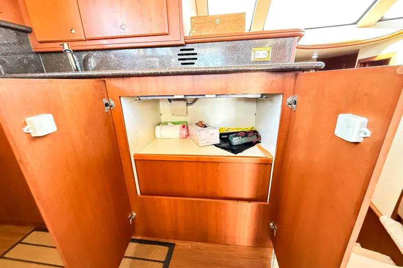 Slide: The Image of Open cabinet in 2004 Silverton 48 Convertible yacht kitchen, showing storage space and items. - 68