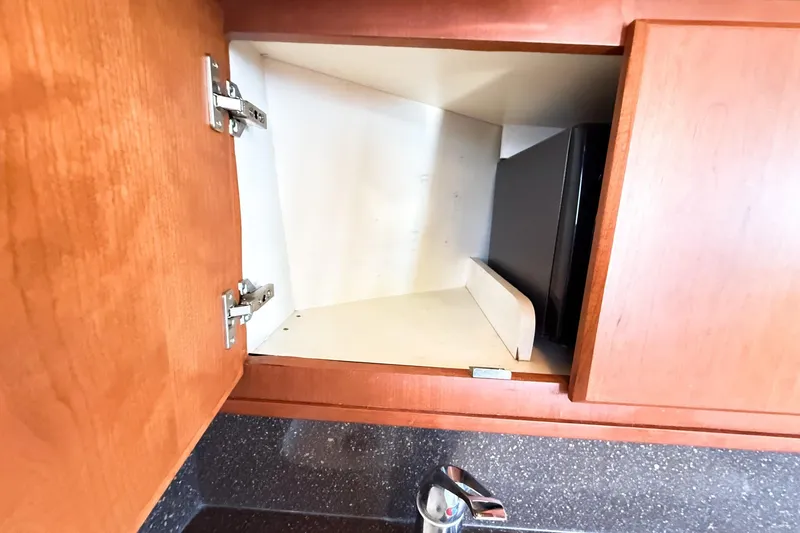 Slide: The Image of Open wooden cabinet on 2004 Silverton 48 Convertible yacht, revealing interior storage space. - 69