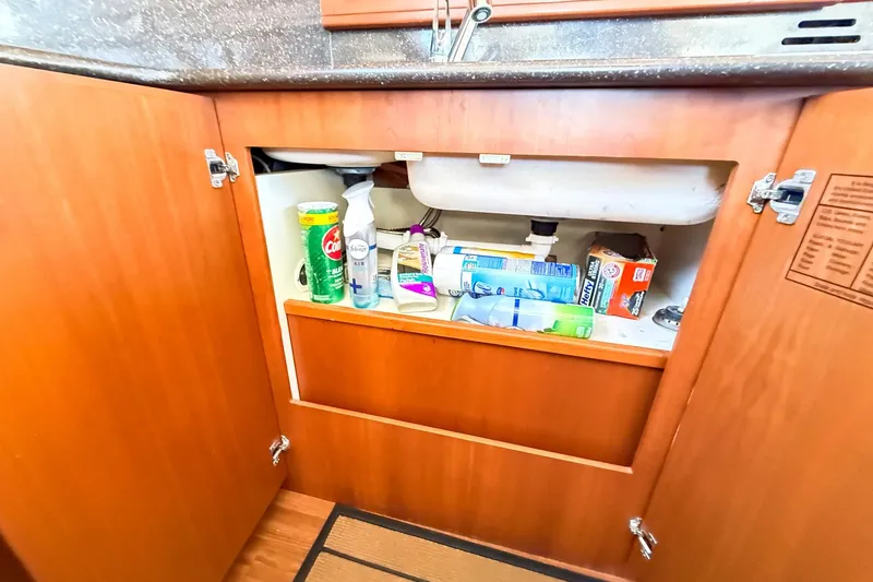 Slide: The Image of Open cabinet under sink with cleaning supplies on a 2004 Silverton 48 Convertible yacht. - 71