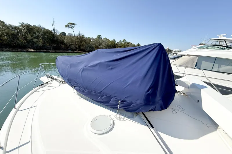 Slide: The Image of 2004 Silverton 48 Convertible yacht with blue cover on deck, docked near trees. - 73