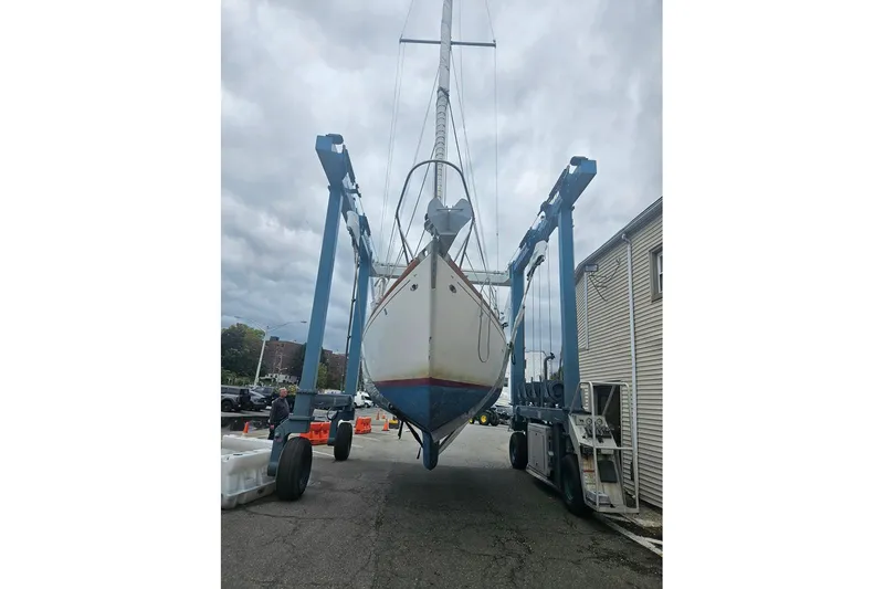 Slide: The Image of 1969 Tartan 37 sailboat on a lift, ready for maintenance under cloudy skies. - 16