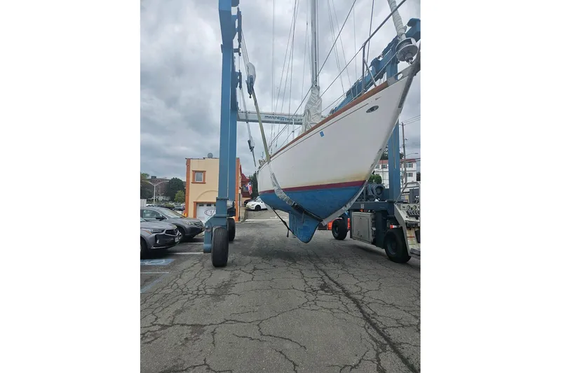 Slide: The Image of 1969 Tartan 37 sailboat being lifted by a marina crane on a cloudy day. - 17