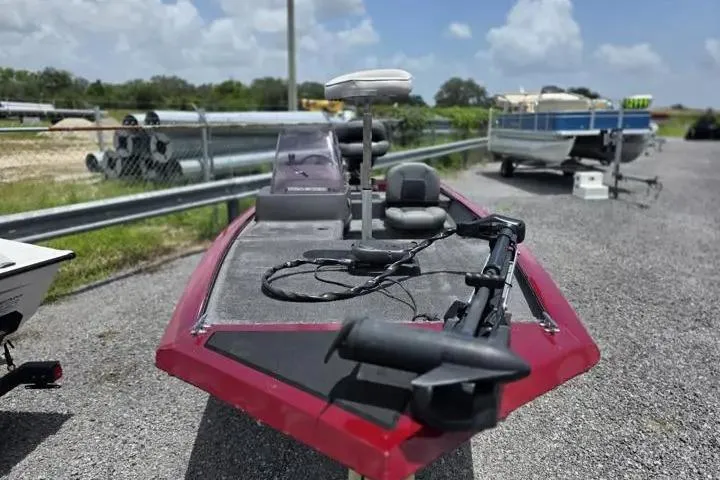 Slide: The Image of 2020 Tracker Pro 160 boat with red trim, parked on gravel lot under a cloudy sky. - 16
