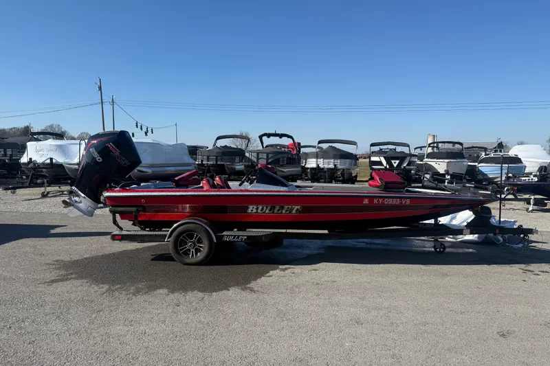 Slide: The Image of 2021 Bullet 21XRD boat interior with red and gray seating, steering console, and carpeted floor. - 11