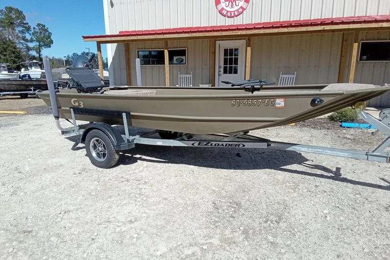 Slide: The Image of 2024 G3 Gator Tough 1652 VBW boat on trailer, parked outside a building. - 21