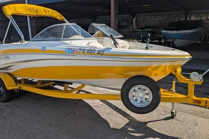 The Image of Yellow 2012 Tahoe Q5L I/O boat on trailer, parked in a covered area. - 0