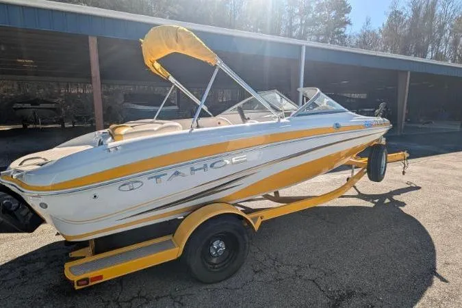 Slide: The Image of 2012 Tahoe Q5L I/O boat on trailer, yellow and white design, parked outdoors. - 2