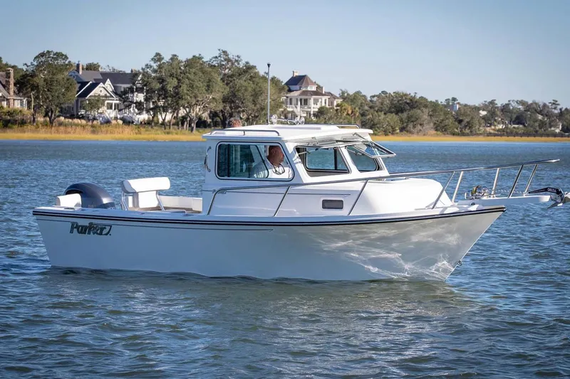 Slide: The Image of 2026 Parker 217 Explorer boat cruising on a serene lake with houses in the background. - 9