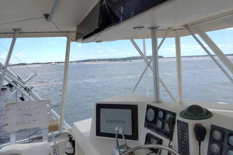Slide: The Image of 1999 Viking 45 Convertible boat helm with Garmin navigation, overlooking calm waters. - 11