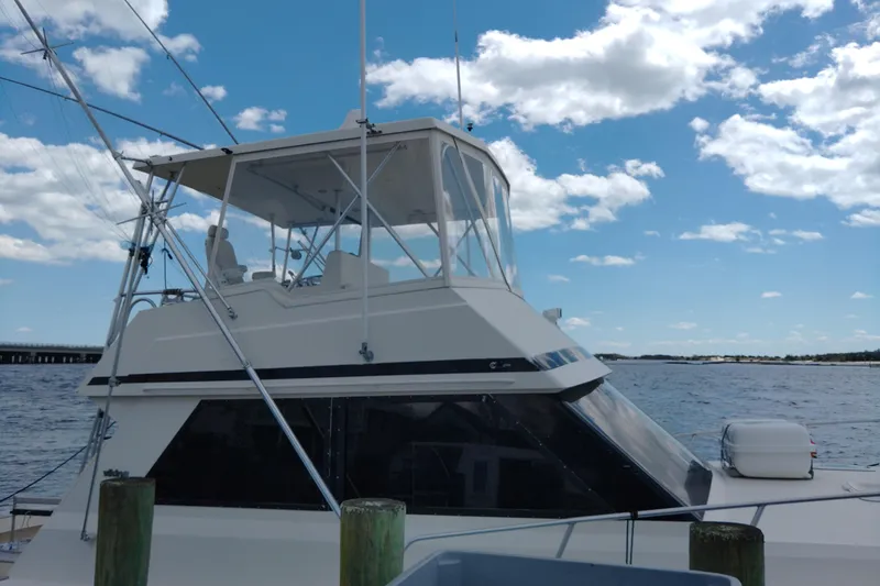 Slide: The Image of 1999 Viking 45 Convertible yacht docked under a blue sky with clouds. - 3