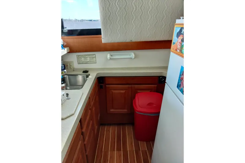 Slide: The Image of 1999 Viking 45 Convertible yacht kitchen with wooden cabinets and red trash bin. - 37