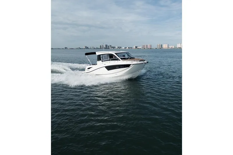 Slide: The Image of 2026 Trophy T25EX EXPLORER OB boat cruising on open water with city skyline backdrop. - 2