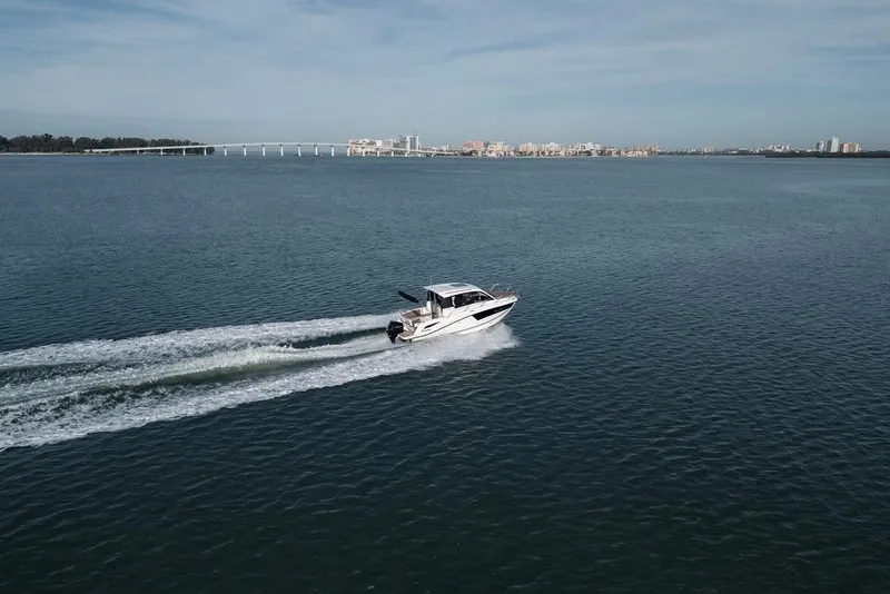 Slide: The Image of 2026 Trophy T25EX EXPLORER OB cruising on open water with cityscape in background. - 6