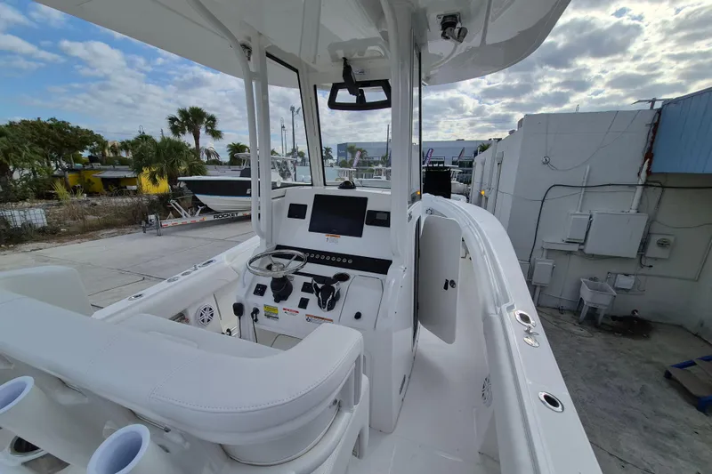 Slide: The Image of 2026 Regulator 25 boat interior with modern helm and seating, docked under cloudy sky. - 13