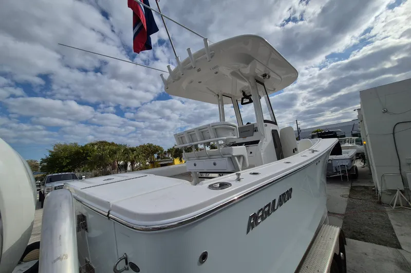 Slide: The Image of 2026 Regulator 25 boat with T-top and flags, docked under cloudy sky. - 19