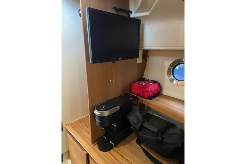 Slide: The Image of 2026 Ranger Tug R-27 interior with TV, coffee maker, and porthole window. - 11