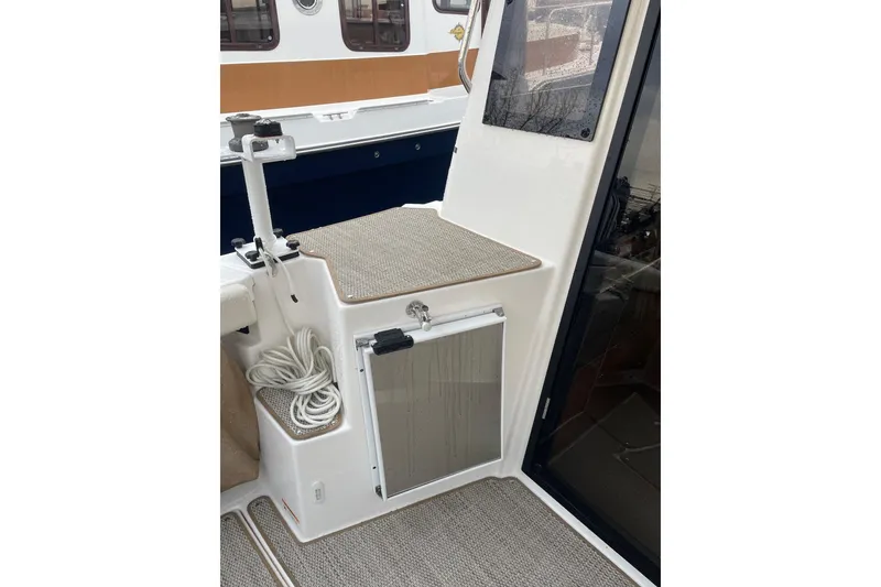 Slide: The Image of 2026 Ranger Tug R-27 boat interior with seating, storage, and coiled rope. - 5