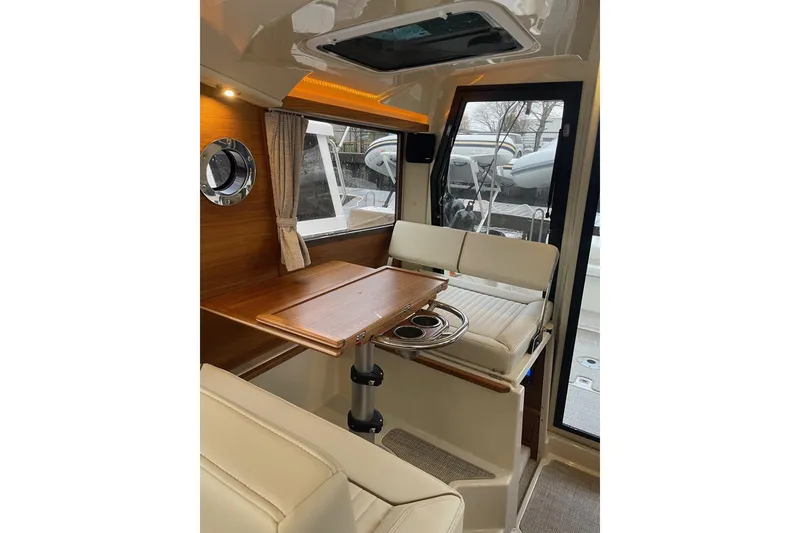 Slide: The Image of 2026 Ranger Tug R-27 interior with wooden table, cushioned seating, and window view. - 8