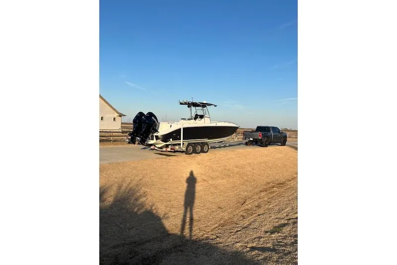 Slide: The Image of 2002 Baja 340 Islander Outboard on trailer, towed by a truck under clear blue sky. - 4