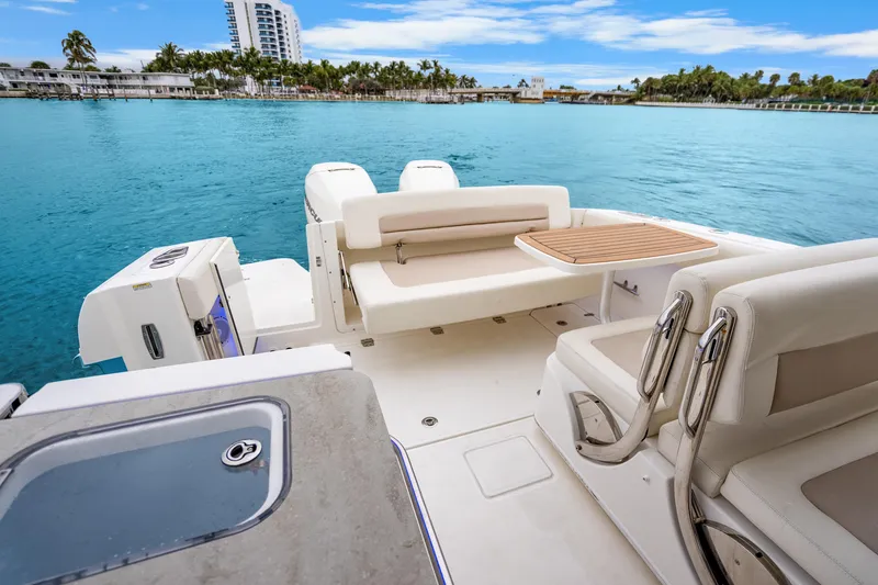 Slide: The Image of 2018 Boston Whaler 320 Vantage boat interior with seating and table on calm water. - 40