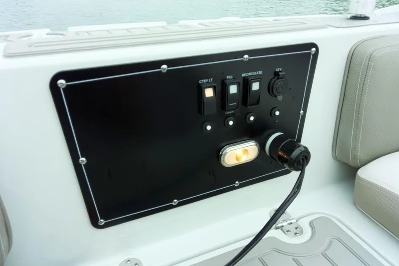 Slide: The Image of Control panel on 2024 Crownline Eclipse E210 XS boat, featuring switches and power outlet. - 12