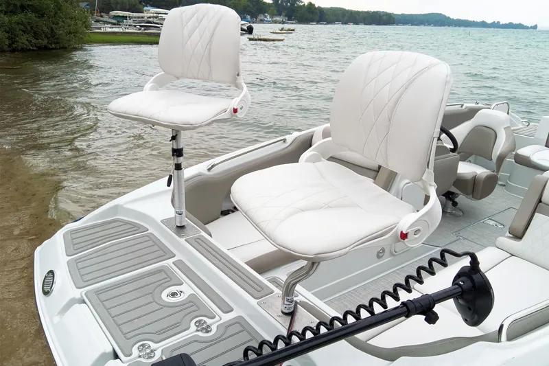 Slide: The Image of 2024 Crownline Eclipse E210 XS boat with white swivel seats by the water. - 13