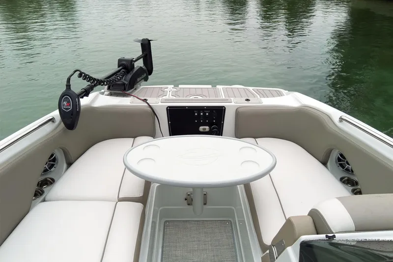 Slide: The Image of 2024 Crownline Eclipse E210 XS boat interior with seating and table on calm water. - 21