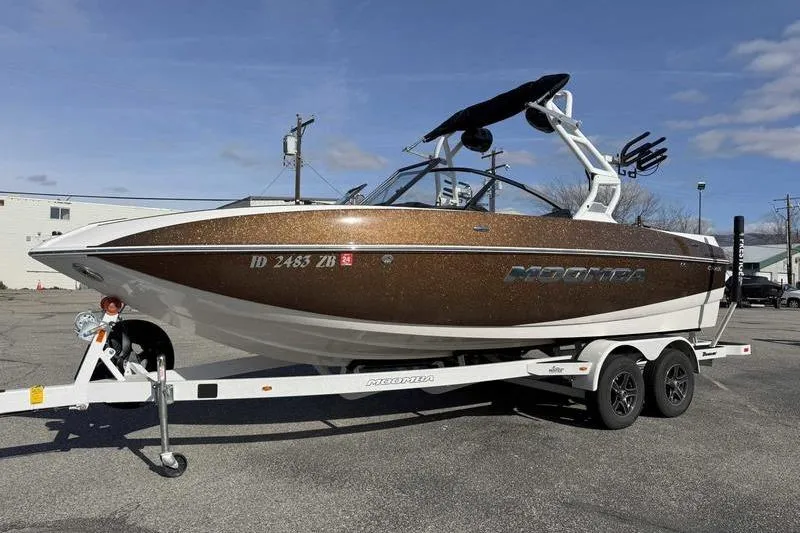 The Image of 2022 Moomba Craz boat on trailer, brown exterior, parked outdoors under blue sky. - 1