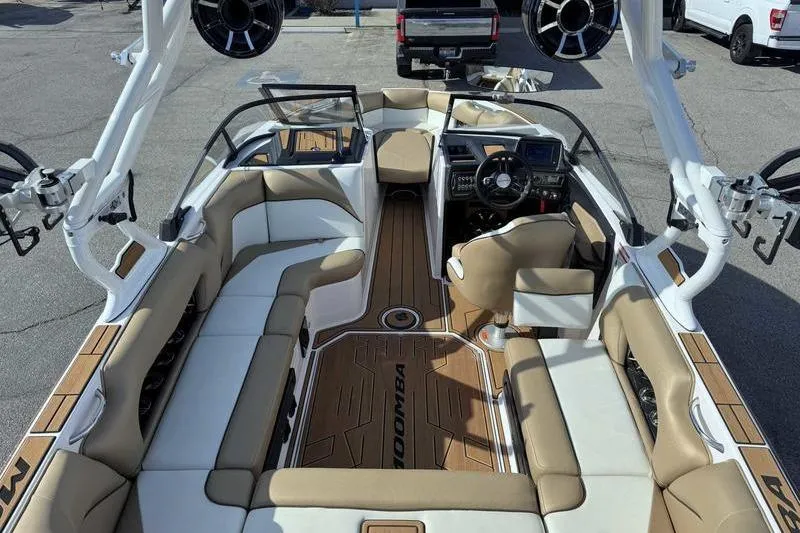Slide: The Image of 2022 Moomba Craz boat interior with tan and white seating, advanced dashboard, and spacious layout. - 11