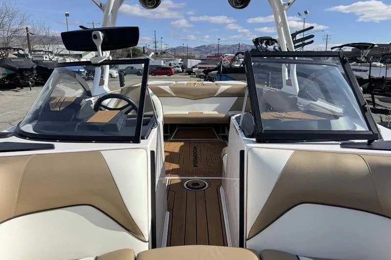 Slide: The Image of 2022 Moomba Craz boat interior with tan and white seating, open windshield, and wood flooring. - 15