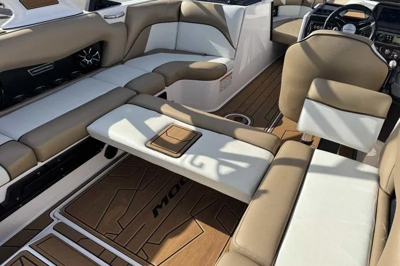 Slide: The Image of 2022 Moomba Craz boat interior with tan and white seating, modern design, and wood-style flooring. - 16