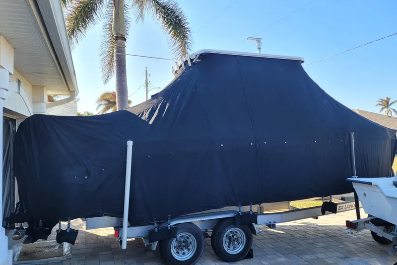 Slide: The Image of 2008 Pro-Line 24 Super Sport boat covered on trailer, parked near palm trees. - 22