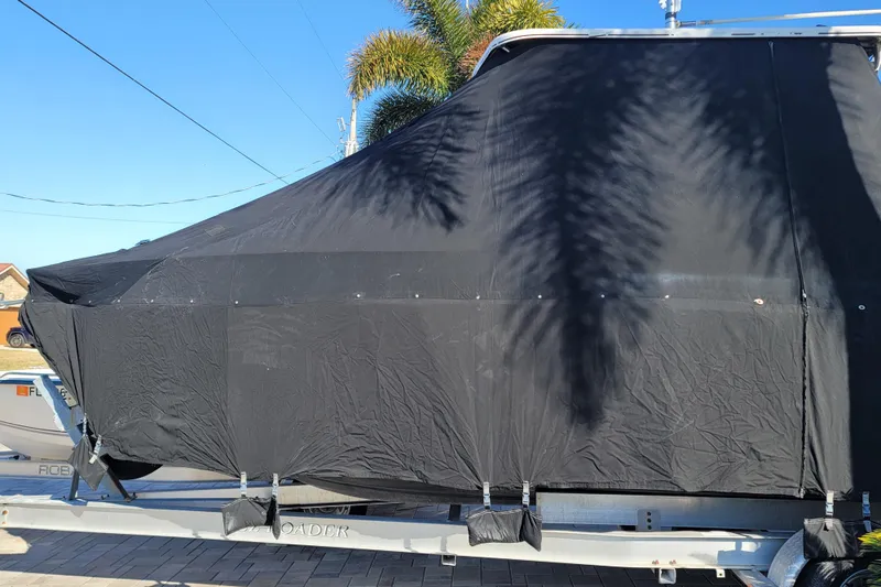 Slide: The Image of 2008 Pro-Line 24 Super Sport boat covered with a black tarp on a trailer. - 24