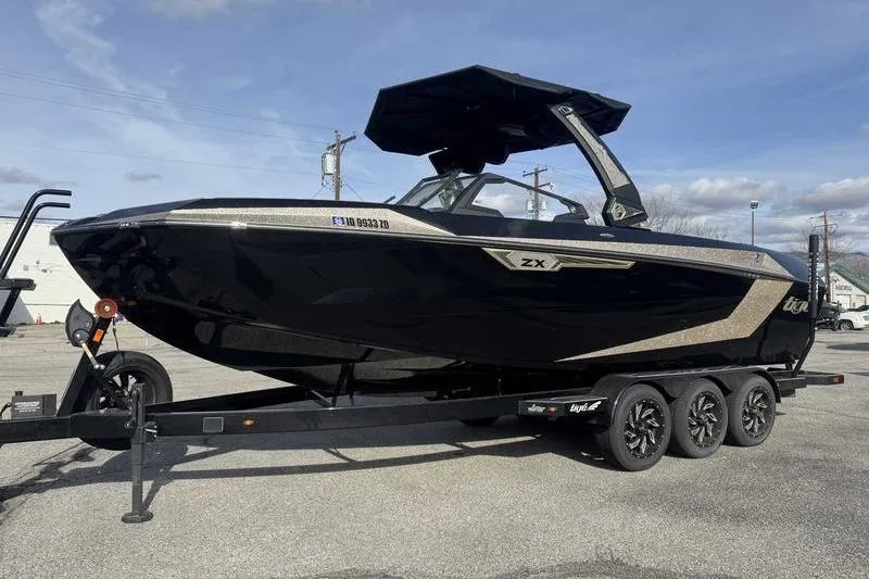 The Image of 2025 Tigé Ultré 25ZX boat on trailer, sleek black design, parked outdoors. - 0