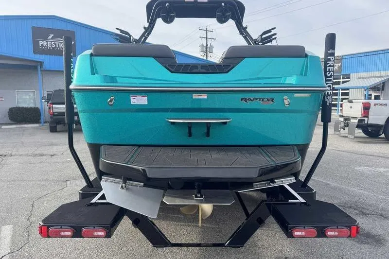 Slide: The Image of 2026 Moomba Tykon boat rear view, turquoise color, on trailer at dealership. - 7