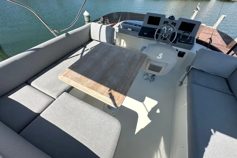 Slide: The Image of Flybridge seating area on 2021 Beneteau Swift Trawler 41 Fly, featuring gray cushions and wooden table. - 3