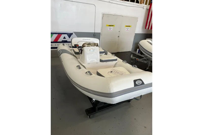 Slide: The Image of 2025 Walker Bay 325 STX Deluxe inflatable boat in showroom, white and gray design. - 5