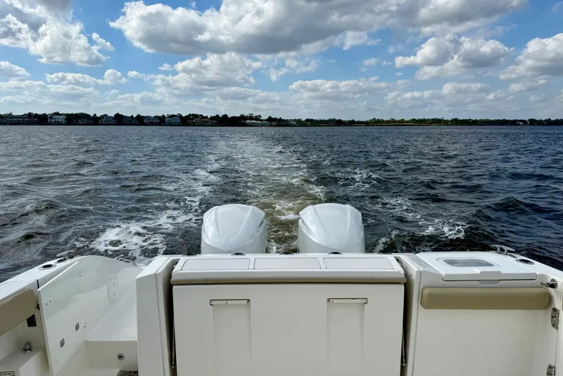 Slide: The Image of 2019 Pursuit S 328 Sport boat cruising on open water under a cloudy sky. - 14