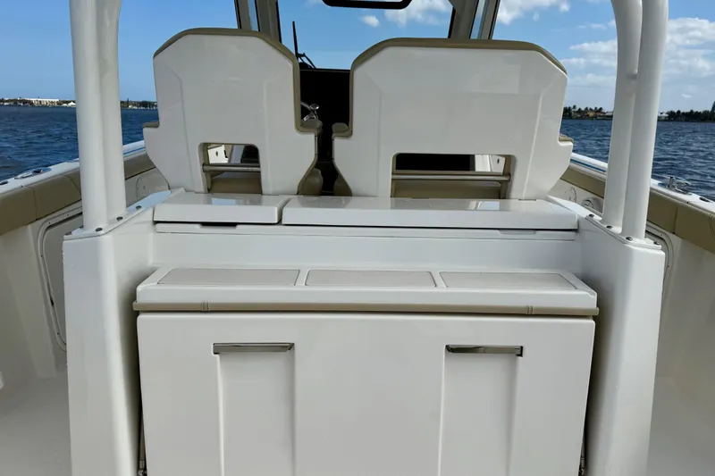 Slide: The Image of 2019 Pursuit S 328 Sport boat interior with seating and storage, on a calm water backdrop. - 17