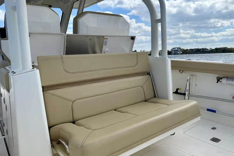 Slide: The Image of 2019 Pursuit S 328 Sport boat with beige seating, on a sunny day by the water. - 19
