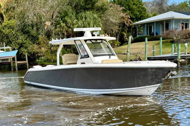 Slide: The Image of 2019 Pursuit S 328 Sport boat cruising on a scenic waterway near a house. - 2